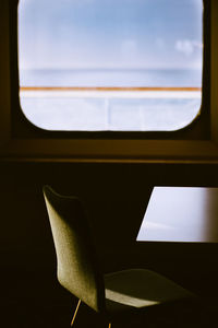 Empty chairs and table against sky seen through window