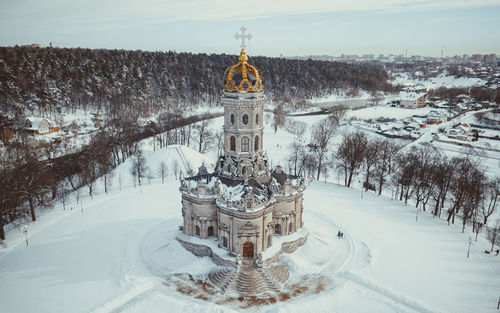 Snow covered trees by building against sky