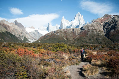 Rear view of men walking on mountain against sky in autumn