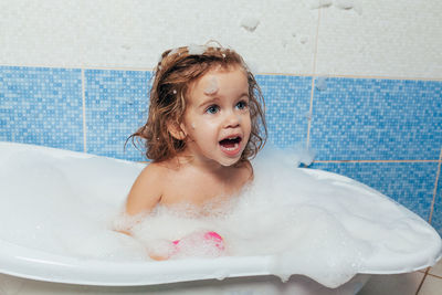 Cute girl sitting in bathtub