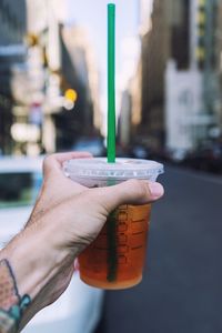 Cropped hand holding drink in city