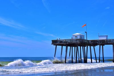 Lifeguard hut on beach against blue sky