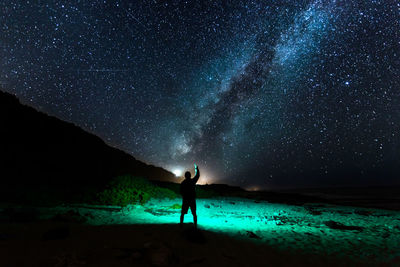 Silhouette person standing on field against sky at night