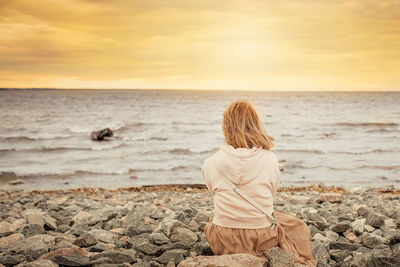 Rear view of woman sitting on beach