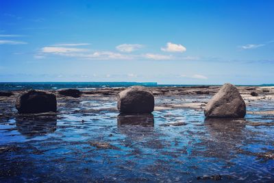 Rocks in sea against blue sky