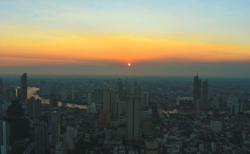 Aerial view of buildings in city during sunset