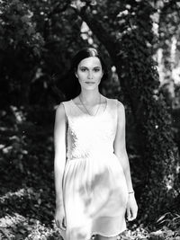 Portrait of young woman standing against tree