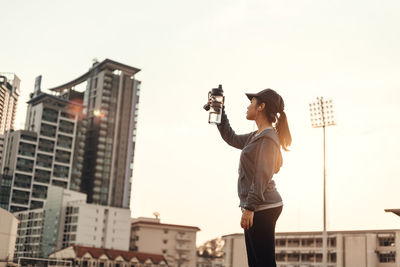 Full length of man photographing on city against sky