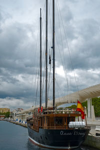 Sailboats moored at harbor against sky