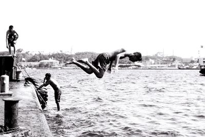 People jumping in sea against clear sky