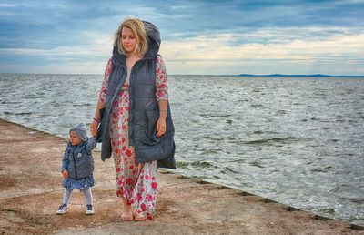 Woman standing by sea against sky