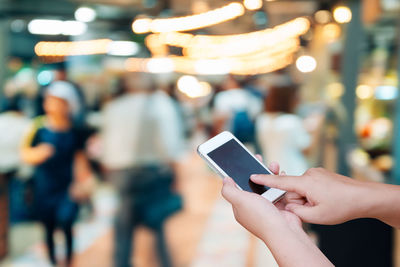 Cropped hand of woman using smart phone in city