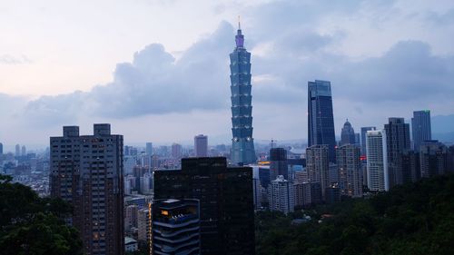 Modern buildings in city against cloudy sky