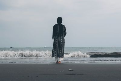 Rear view of woman standing at beach