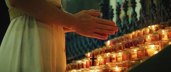 Midsection of woman holding illuminated string lights