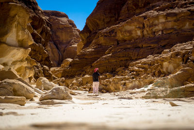 Rear view of man standing against rock formations at mount sinai