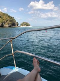 Low section of woman relaxing on boat sailing in sea