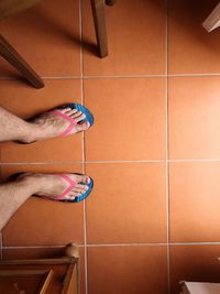 Low section of person standing on tiled floor at home