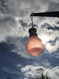 Low angle view of illuminated light bulb against sky