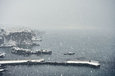 Picturesque seascape with cliff during snowy weather