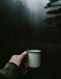 Cropped hand of person holding coffee cup outdoors