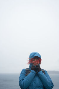 Explorer with backpack and closed eyes standing on rocky hill on cloudy day in autumn