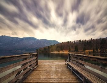 Pier on lake against cloudy sky