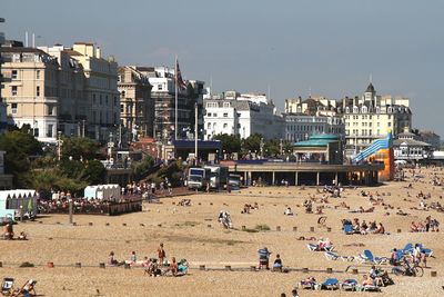 Crowd on beach in city against sky