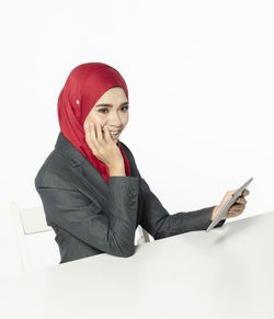 Portrait of smiling man holding smart phone against white background