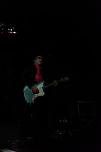 Young man playing guitar against black background