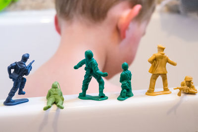 Close-up of boy by toy soldiers on bathtub