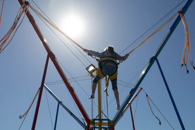 Low angle view of woman bungee jumping against sky