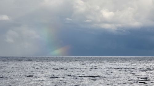 Scenic view of rainbow over sea against sky