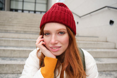 Portrait of young woman standing against wall