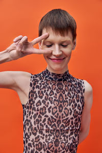 Portrait of young woman standing against yellow background
