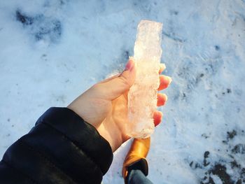 Cropped image of woman holding ice on snowfield