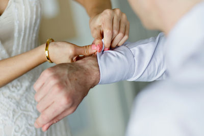 Cropped hand of woman putting man shirt button