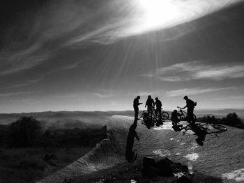 Men with bicycle on mountain against bright sky