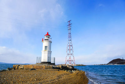 Lighthouse by sea against sky