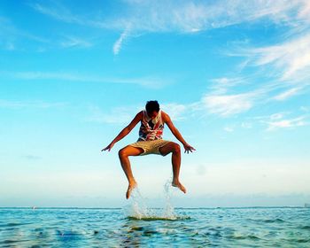 Full length of woman standing in sea against sky