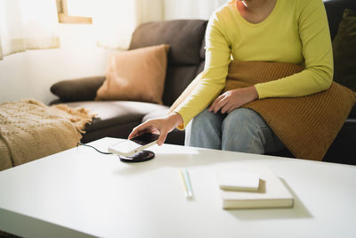 Midsection of woman sitting on sofa at home