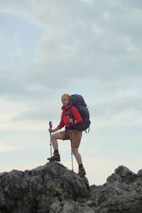 Man standing on rock against sky