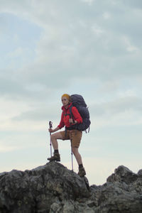 Full length of woman holding hiking poles standing on rocks