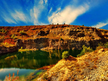 Scenic view of rock by lake against sky