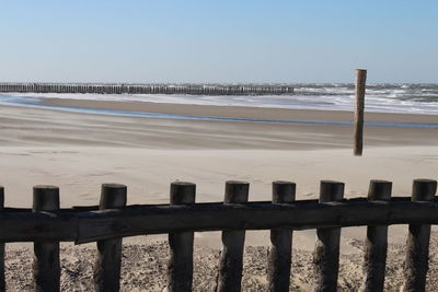 Wooden posts on beach against sky