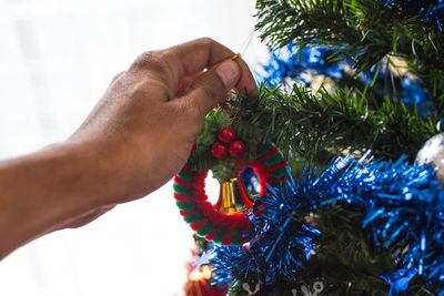 Cropped image of hand holding christmas decoration at home