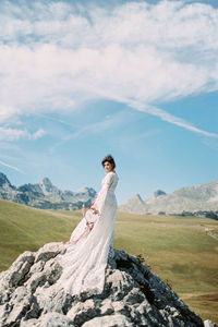 Full length of woman standing on rock against landscape