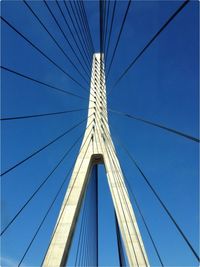 Low angle view of suspension bridge against blue sky