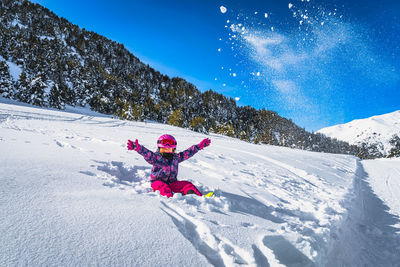 Girl sitting on snow and throwing snow powder up to the air, andorra, pyrenees