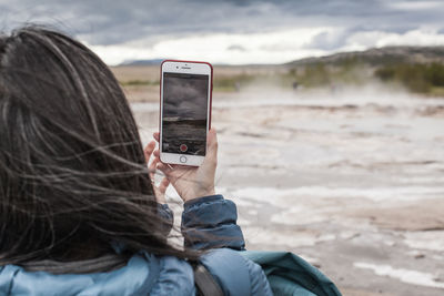 Close-up of person using smart phone against sky